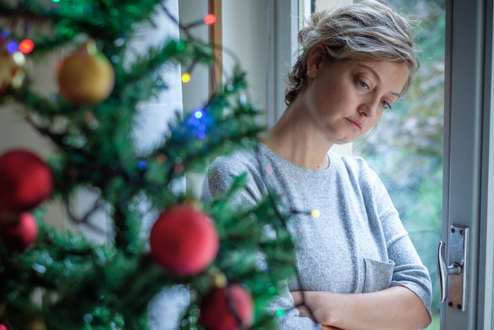 woman standing near a christmas tree as she grieves a miscarriage