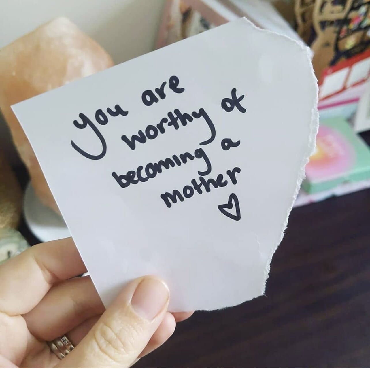 woman holding note that reads you are worthy of becoming a mother