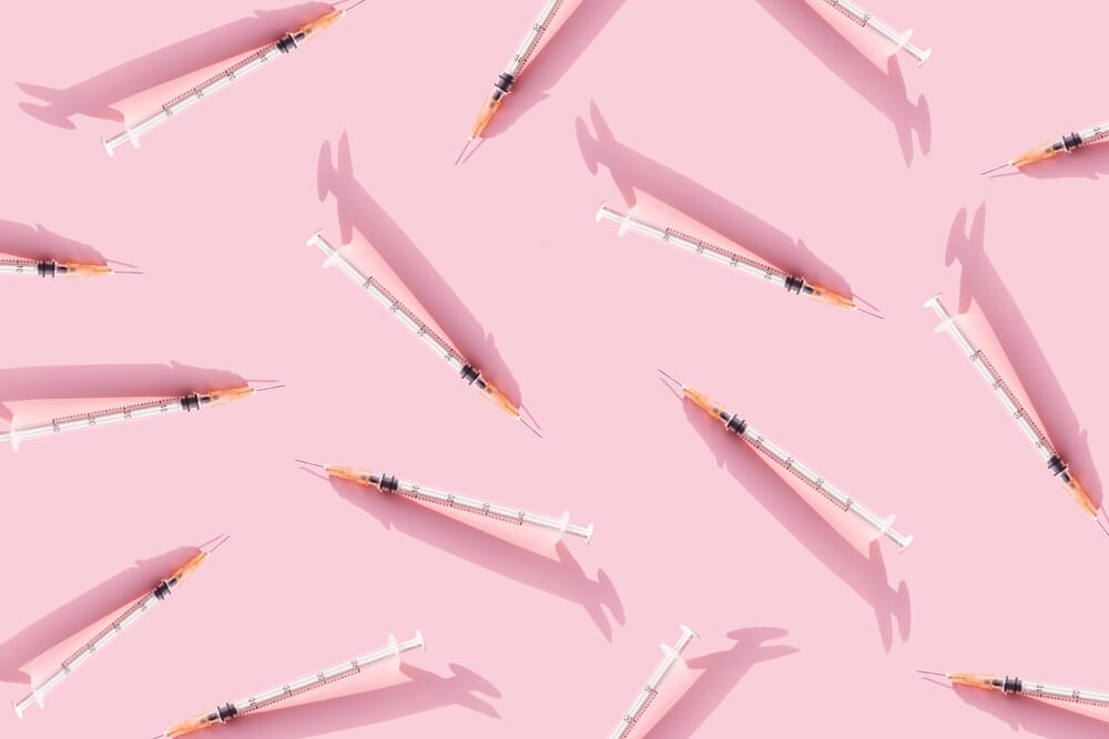 scattered ivf needles on a pink background