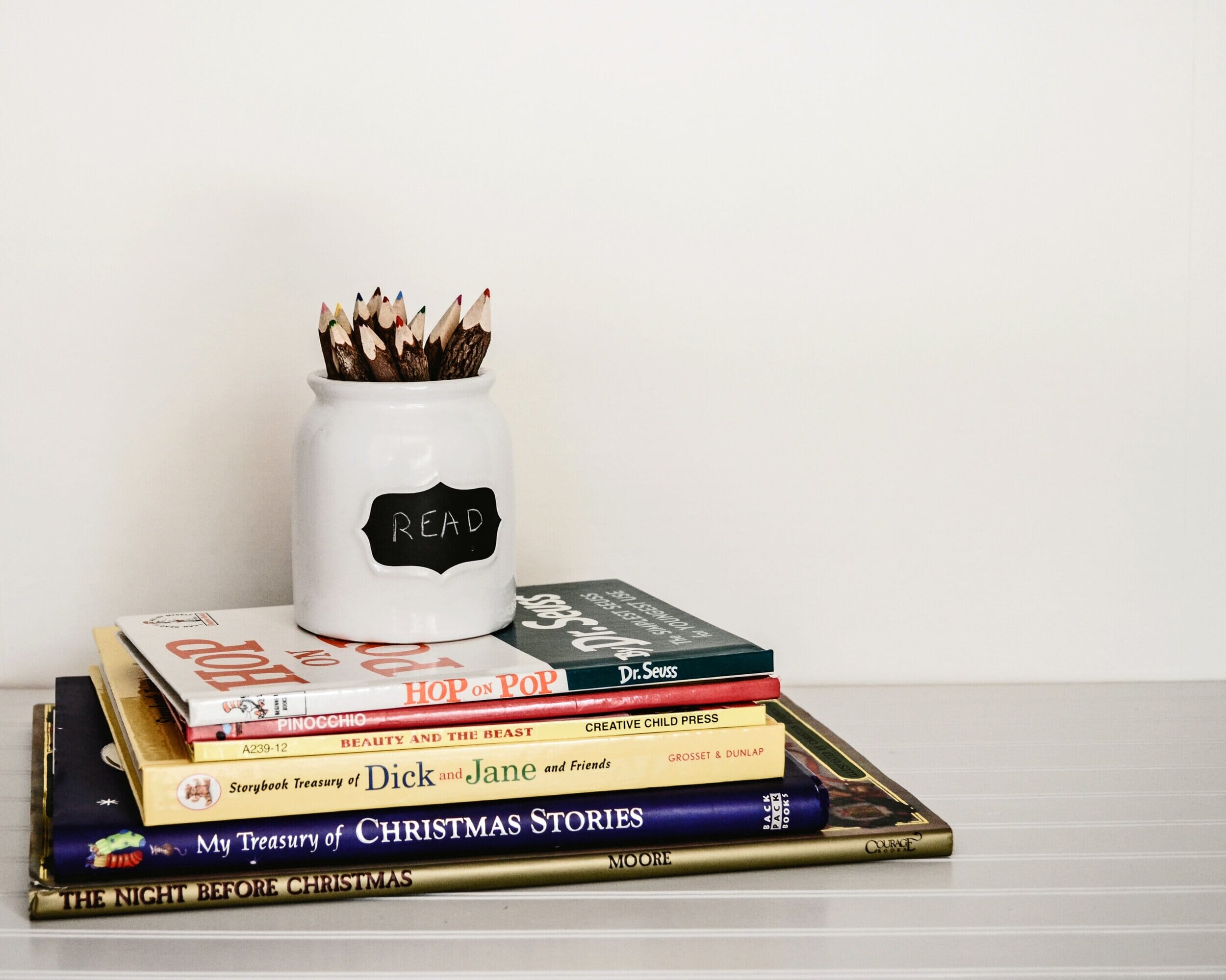 stack of books with cup of pencil on top