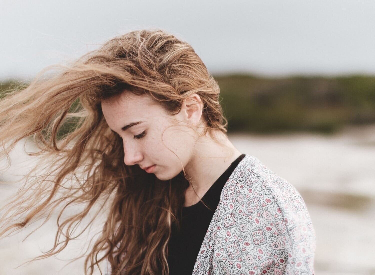 pensive woman walking on the beach wind in her hair