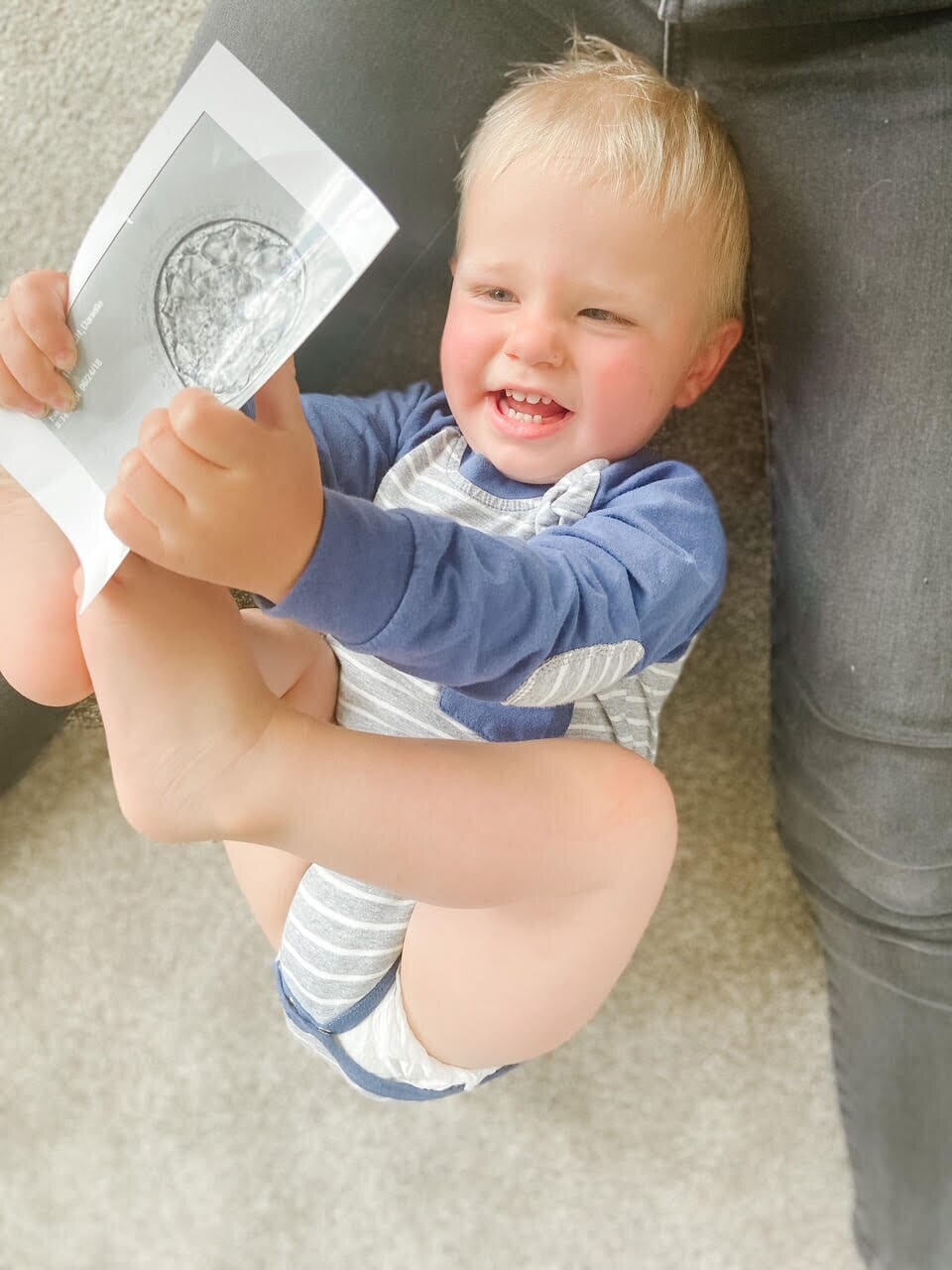 baby boy holding a picture of himself as an embryo