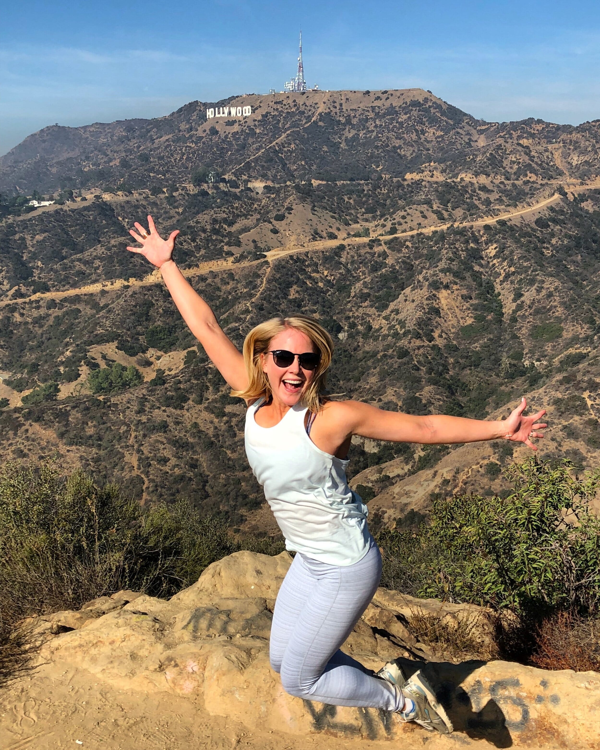 holly waters jumping for joy in front of the hollywood sign
