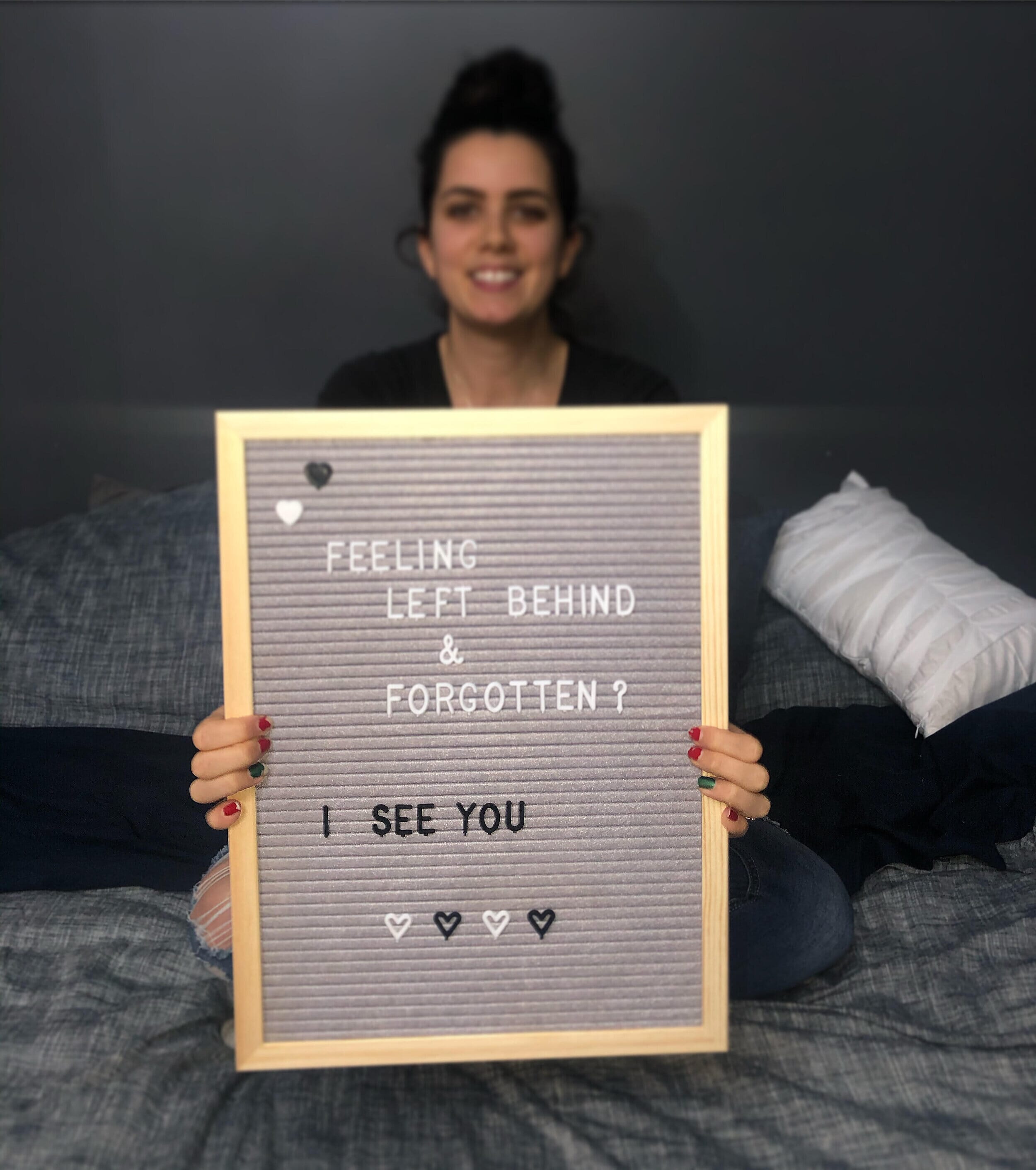 fertility warrior amy baker holding a sign that reads "feeling left behind and forgotten? i see you" 