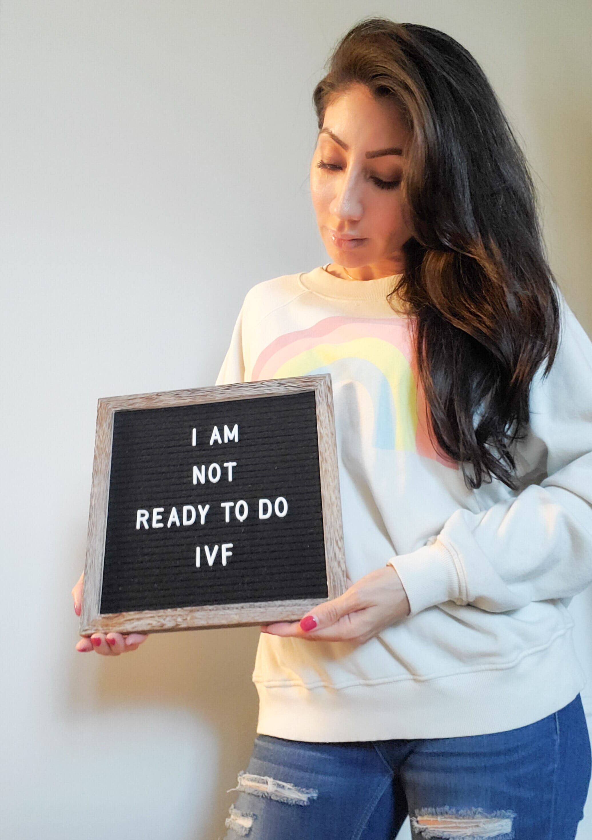 woman holding a sign that reads &quot;i am not ready to do ivf&quot;