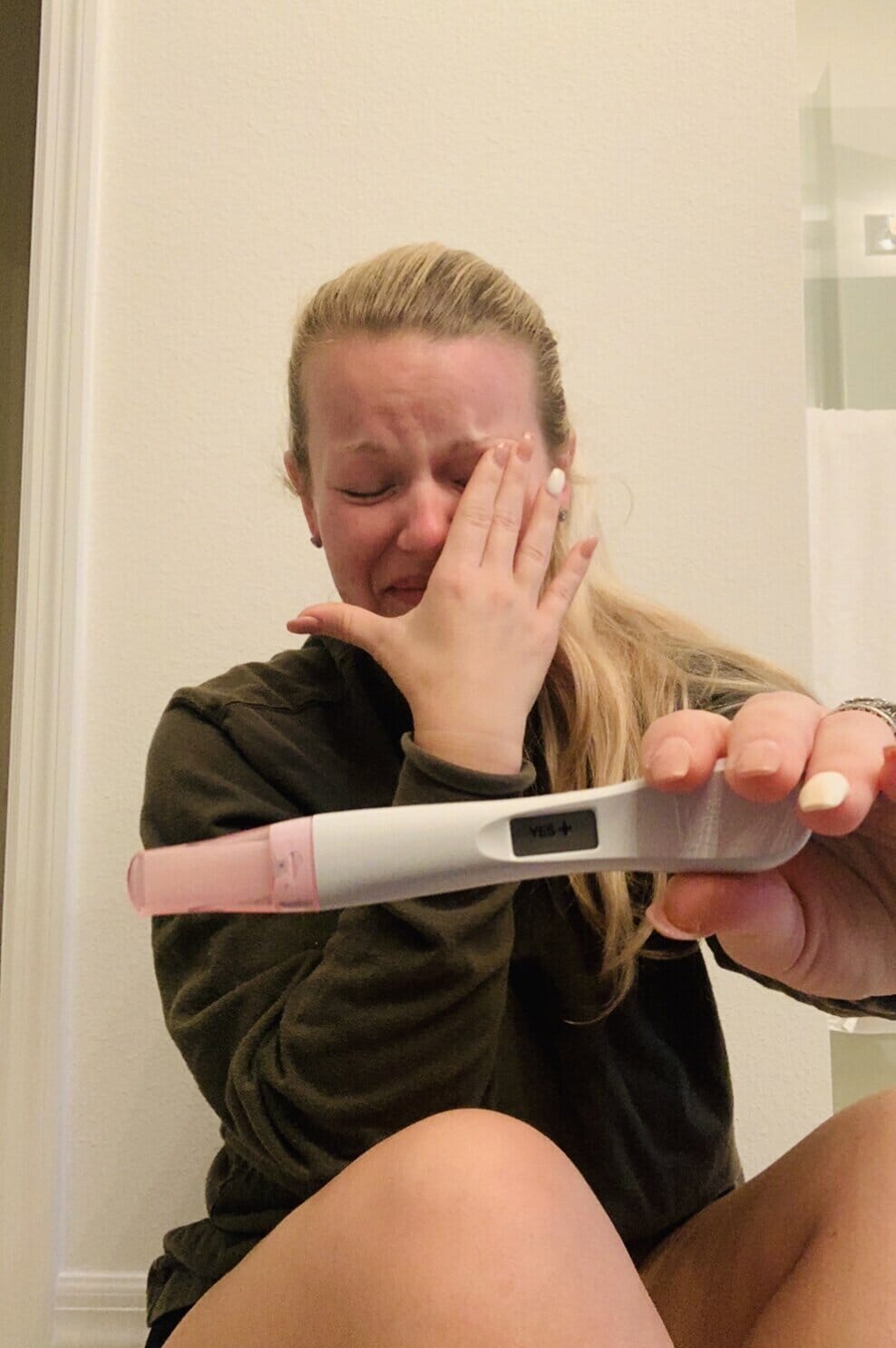 recording artist ashley j. crying and holding a positive pregnancy test