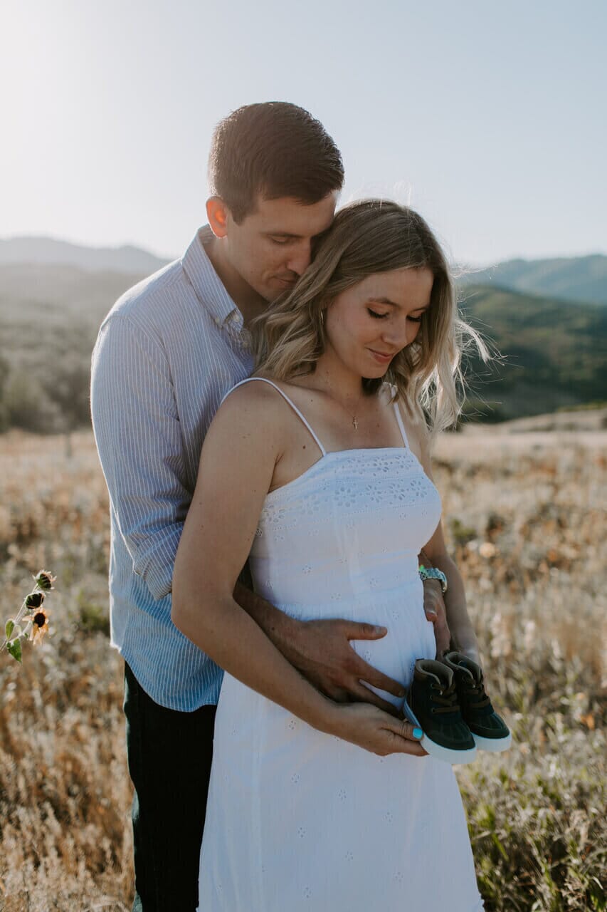 infertility warrior jen lowell and her husband cradling her pregnant belly