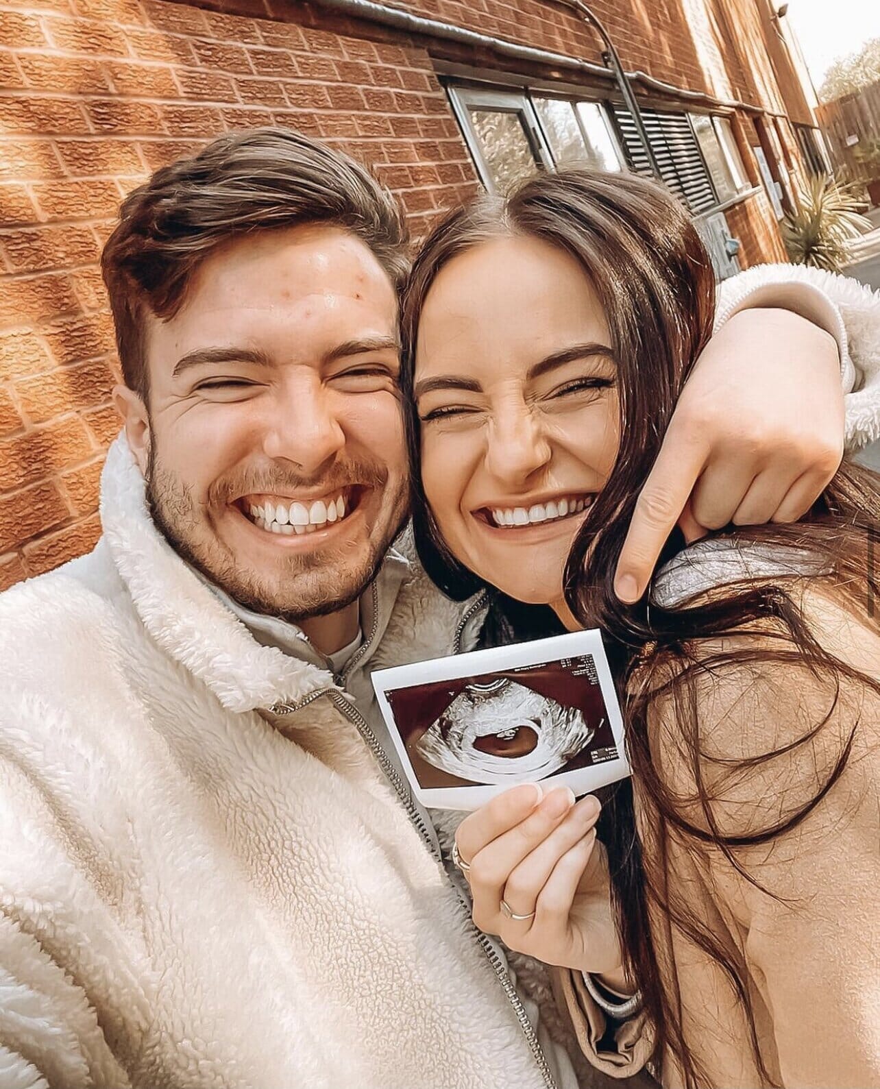 uk ambassador for endometriosis miranda burns and her partner with a sonogram photo of their baby